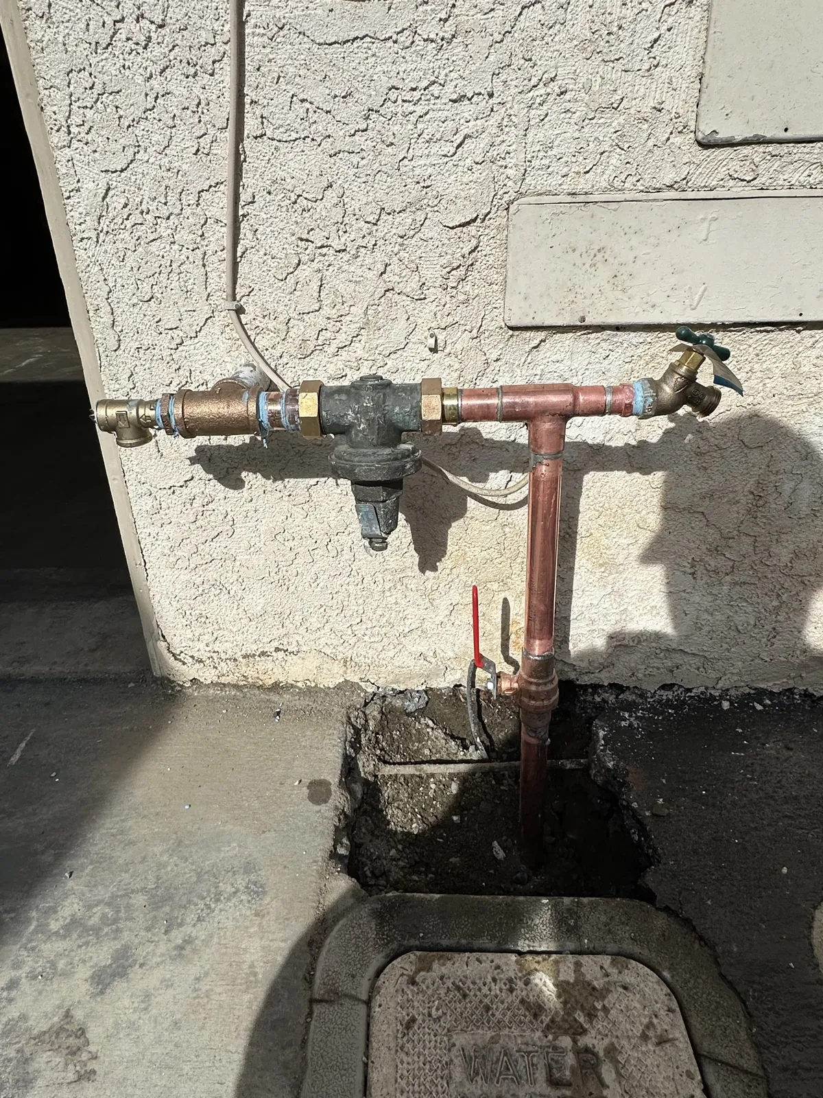 A house water main with its shut-off valve and new copper above an open dig