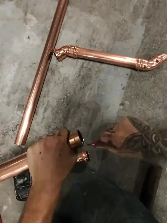 Through Jacob's glasses: copper pipe and elbows laid out on a concrete floor